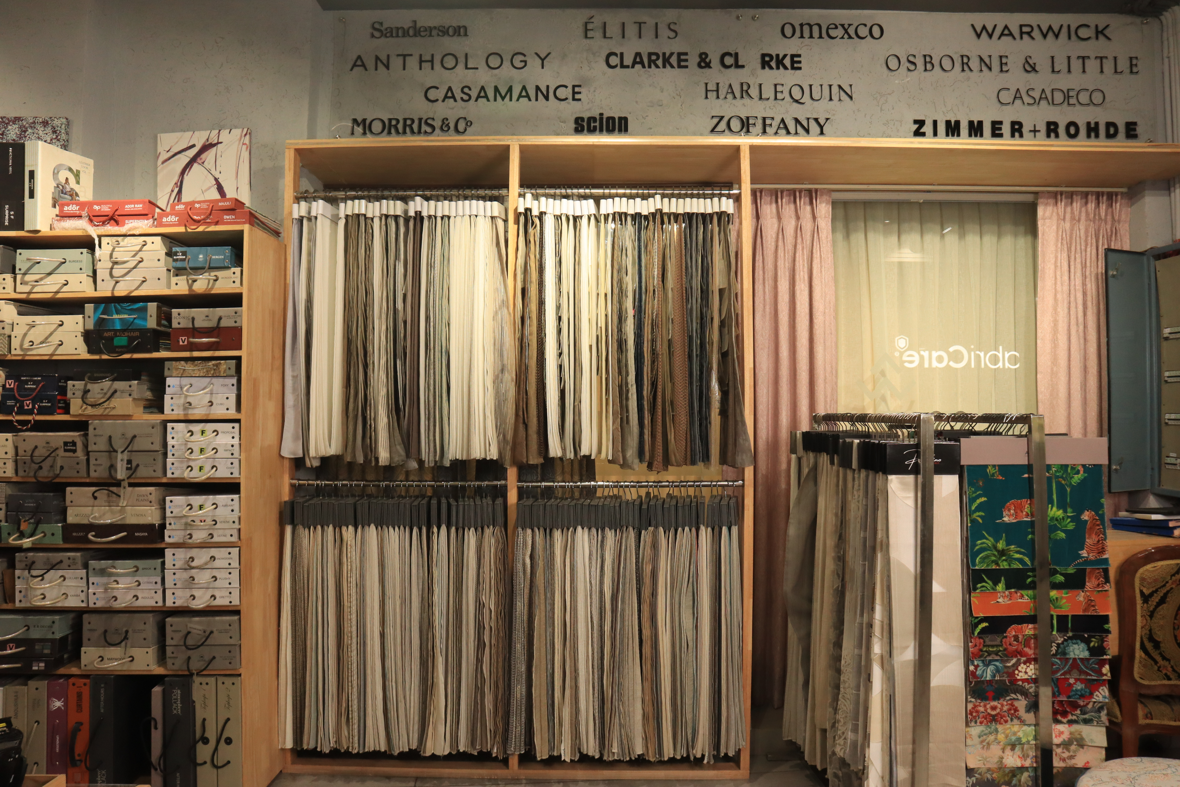 Showroom fabric racks with hanging samples and brand names on the wall