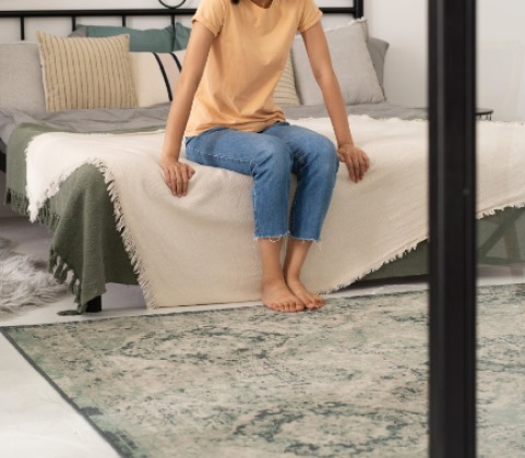 Person seated on bed with fabric samples and rug