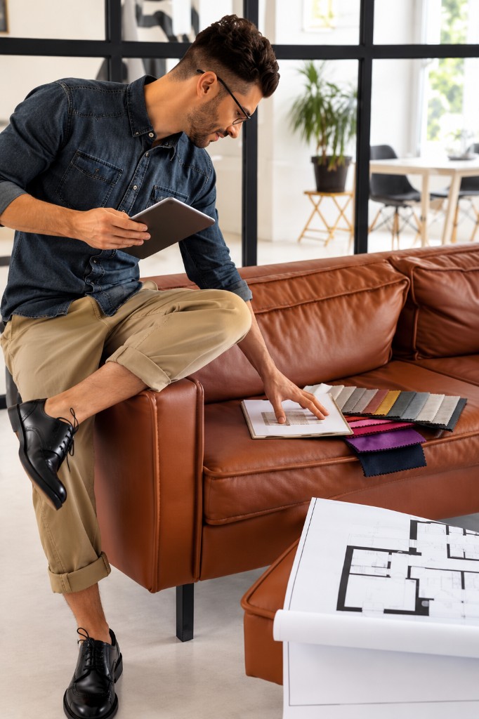 Designer reviewing fabric swatches on leather sofa
